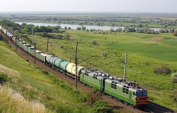 Электровоз тянет по рельсам длинный грузовой состав из цистерн и вагонов
