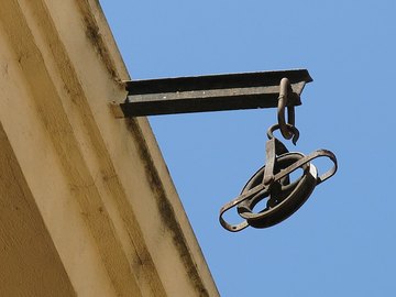 Блок на балке, выступающей из стены дома: колесо с желобком в обойме